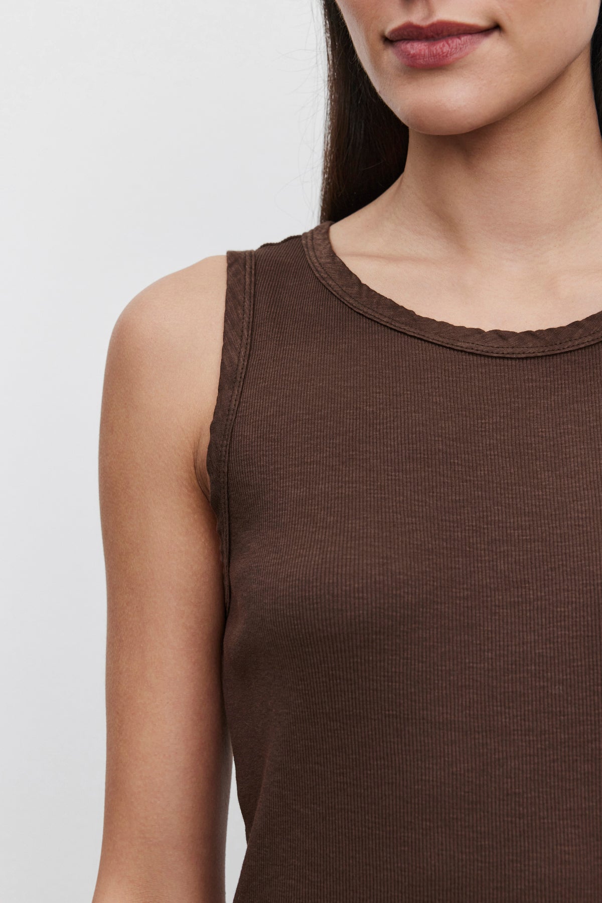   A person wearing the MAXIE RIBBED TANK TOP by Velvet by Graham & Spencer. Only the lower part of the face and upper body are visible, showcasing the soft textured, slub knit fabric in a brown sleeveless design. 