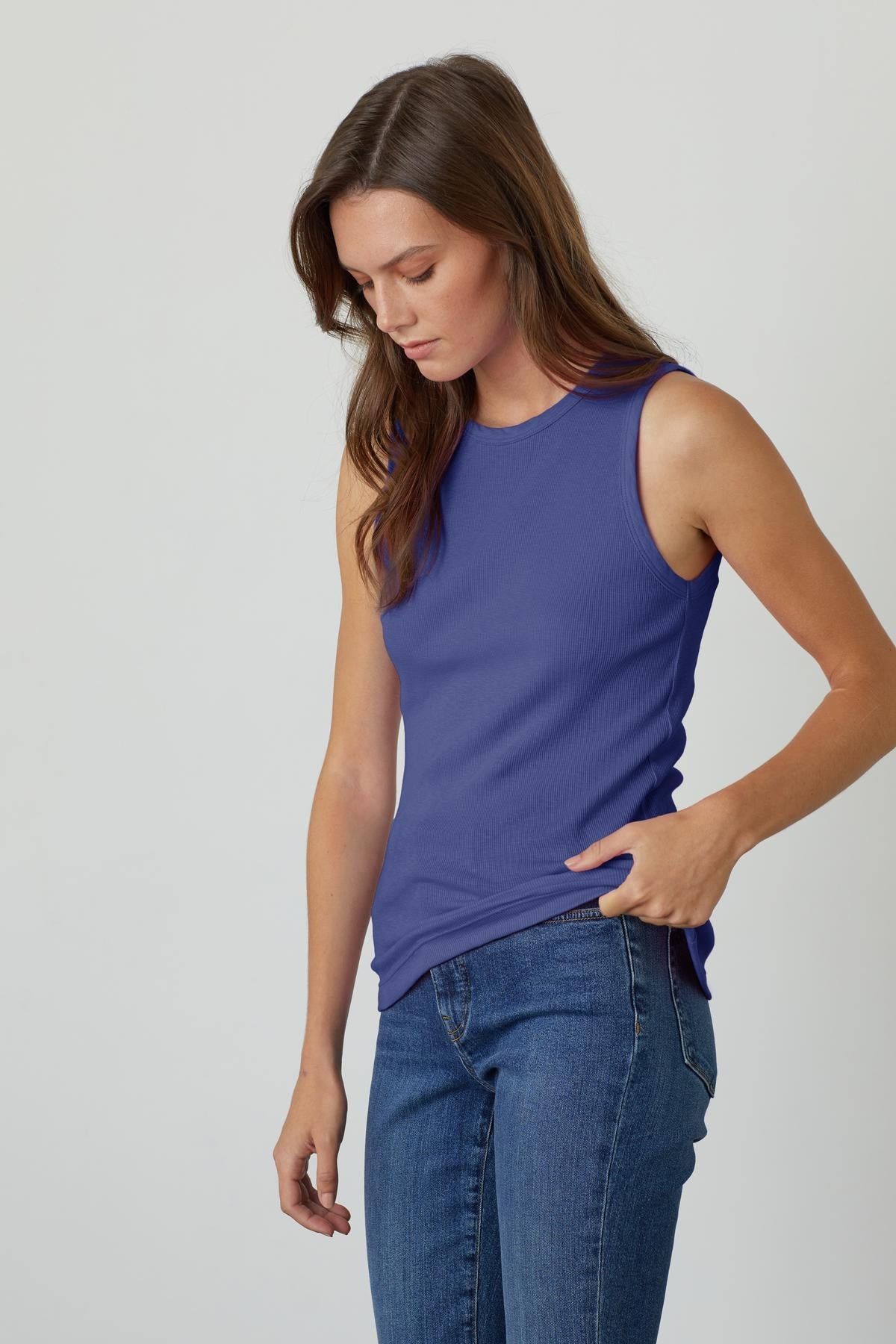   a woman wearing a cavern blue MAXIE RIBBED TANK TOP by Velvet by Graham & Spencer and jeans. 