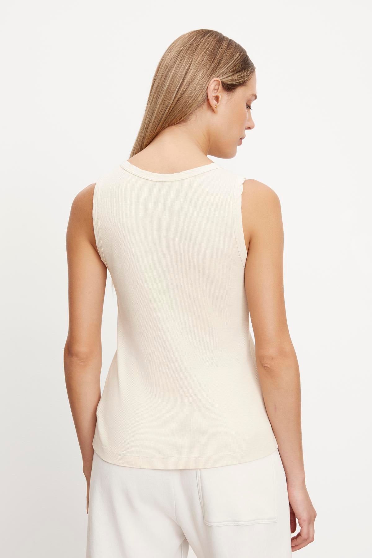   The back view of a woman wearing a Velvet by Graham & Spencer MAXIE RIBBED TANK TOP in her closet. 