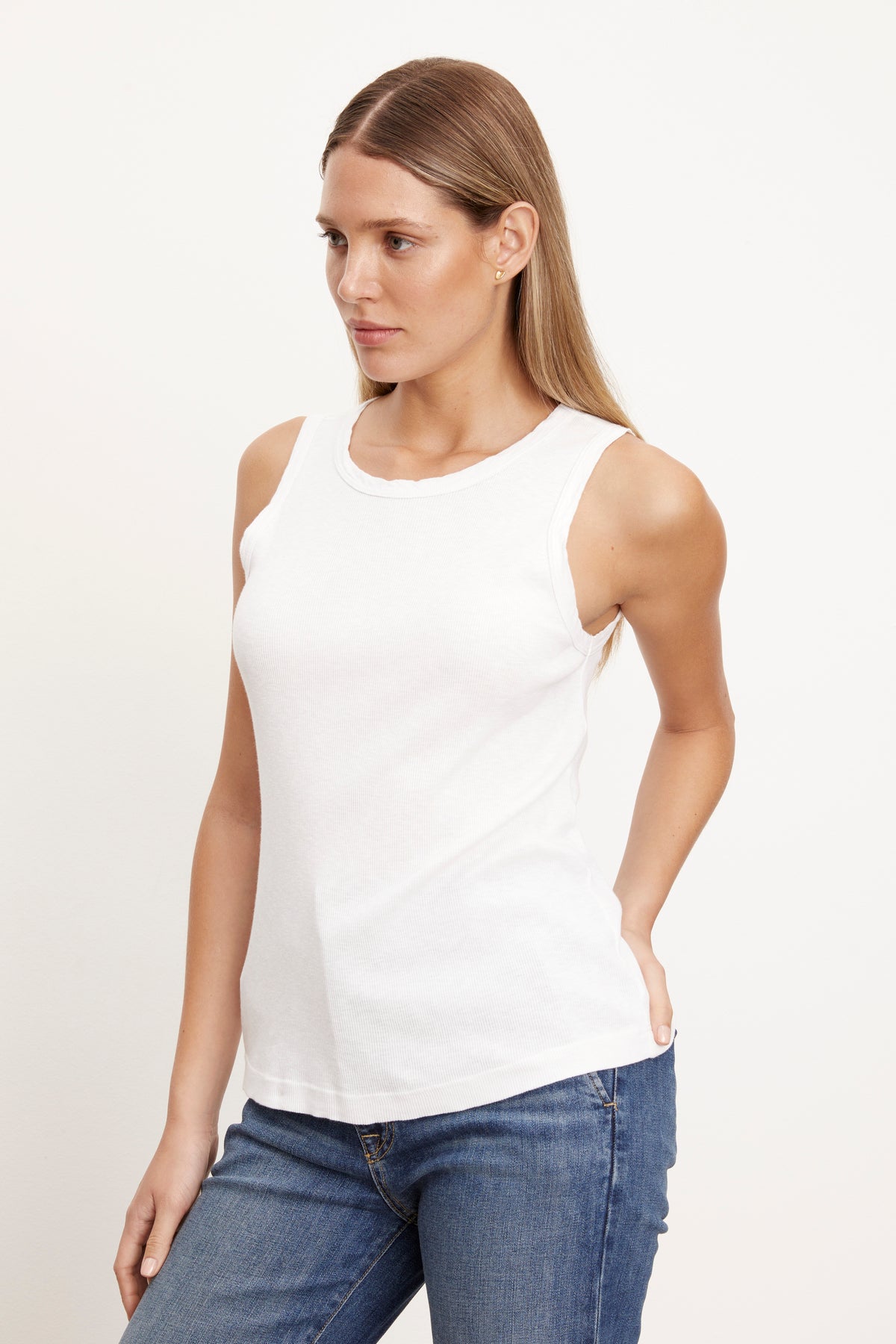   a woman wearing a white MAXIE RIBBED TANK TOP by Velvet by Graham & Spencer and jeans. 