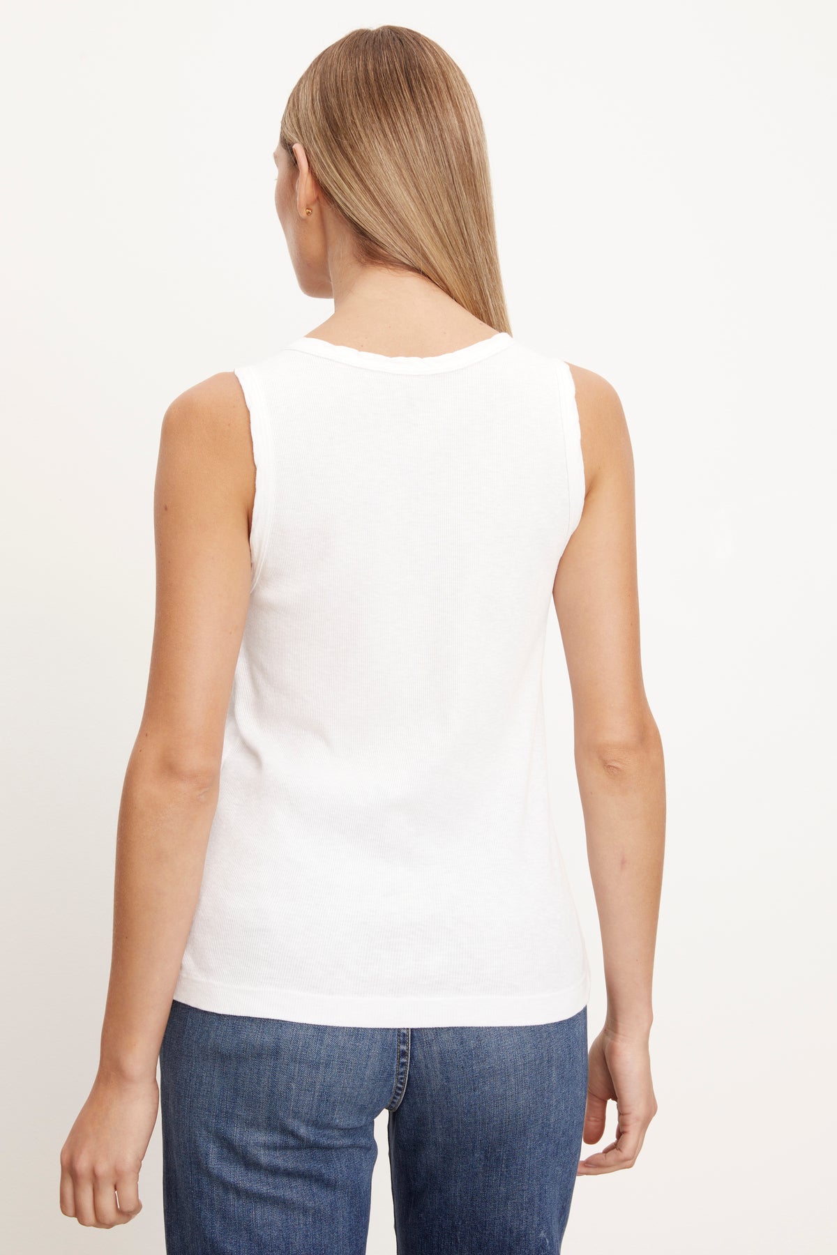 The back view of a woman wearing a Velvet by Graham & Spencer white MAXIE RIBBED TANK TOP.-26514178867393