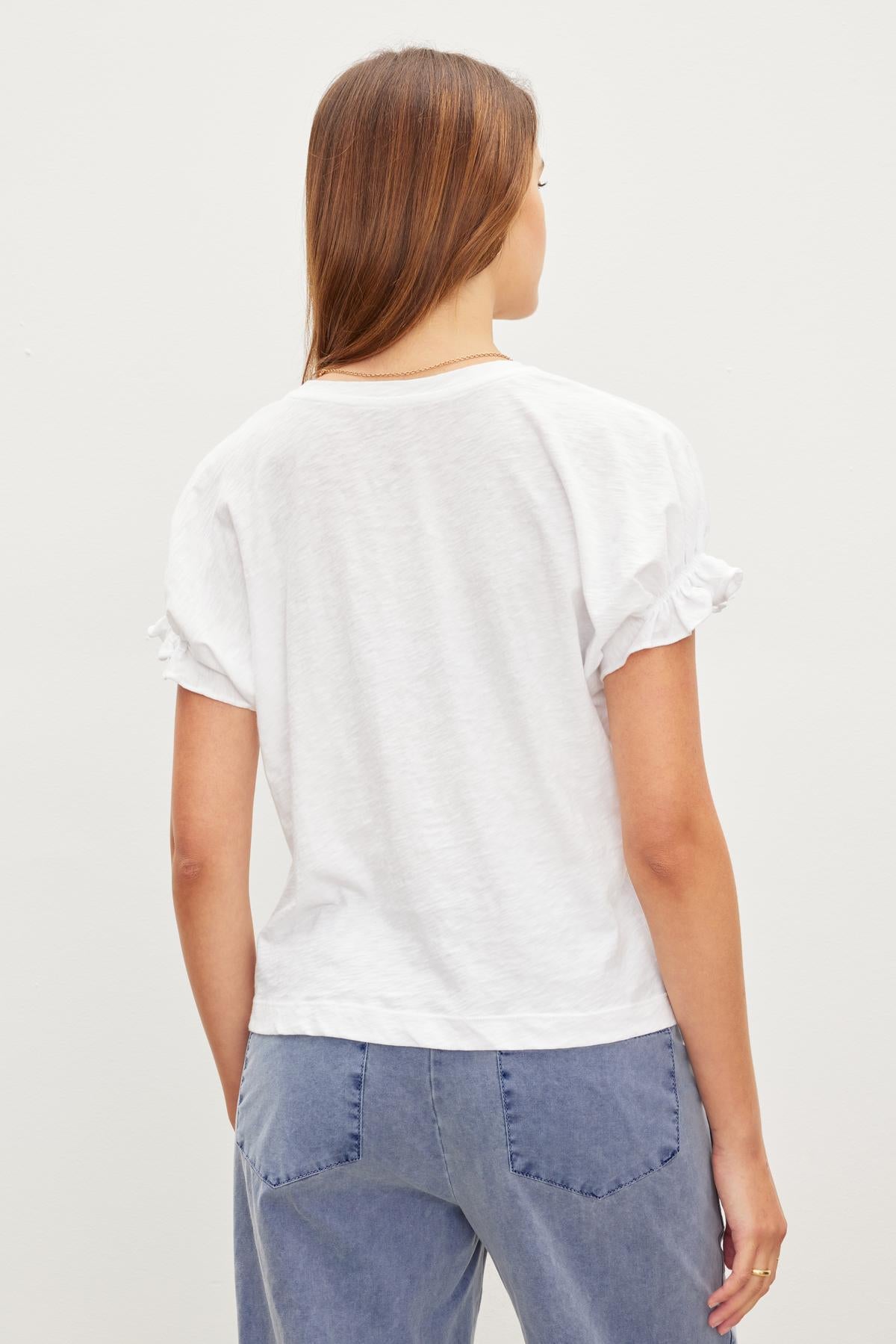   The back view of a woman wearing a white ruffle sleeve MIMI CREW NECK TEE by Velvet by Graham & Spencer. 