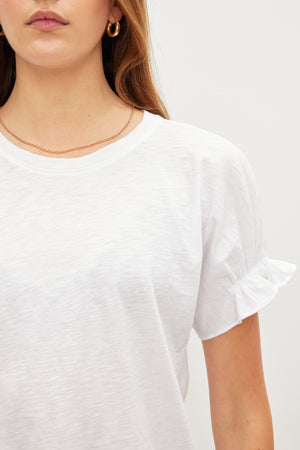 The model is wearing a white MIMI CREW NECK TEE with ruffled sleeves, a wardrobe essential by Velvet by Graham & Spencer.
