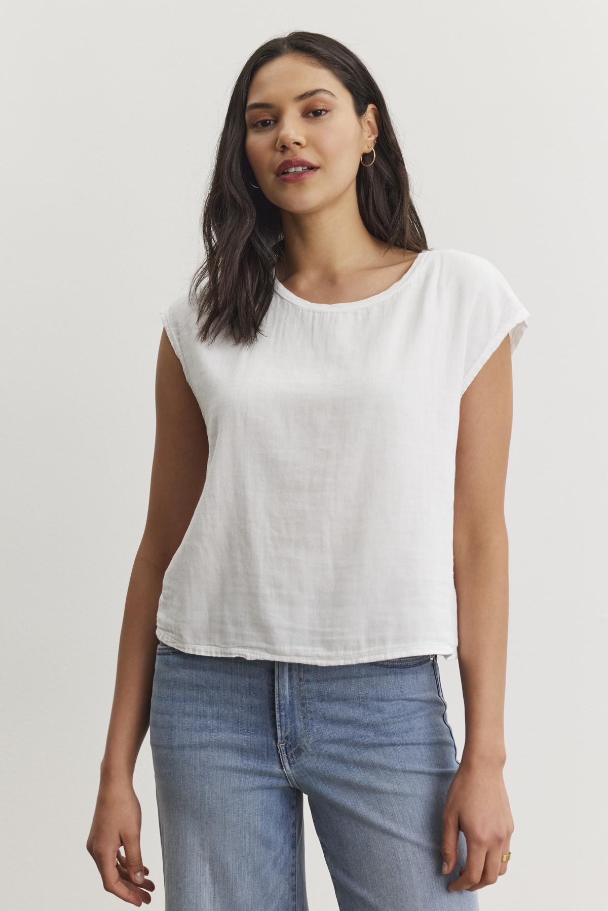 A woman with dark hair, wearing the DANIELLA CREW NECK TEE by Velvet by Graham & Spencer and blue jeans, stands against a plain white background.-37074420990145