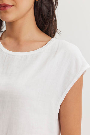 A close-up of a person wearing a white DANIELLA CREW NECK TEE from Velvet by Graham & Spencer made from lightweight cotton woven fabric. Only the lower half of their face and upper torso are visible, offering a casual basic look in a cropped silhouette.