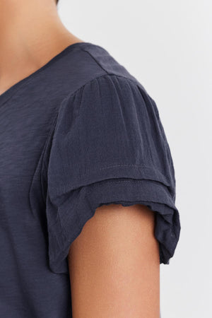 Close-up view of a woman's shoulder wearing a Velvet by Graham & Spencer DELLA TEE with pleated sleeve detail.