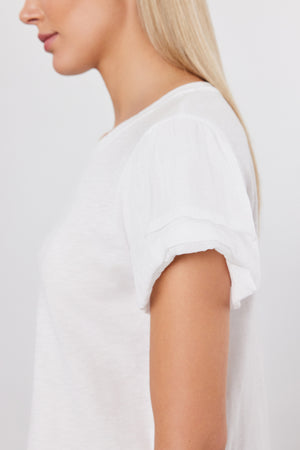 Side profile of a person with long blonde hair, wearing the Velvet by Graham & Spencer DELLA TEE, a white short-sleeved top with pleated sleeves.