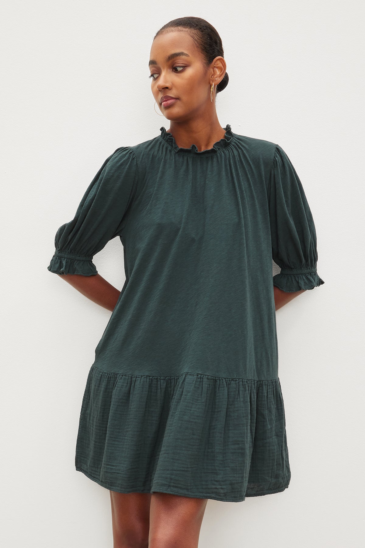 The model is wearing a Velvet by Graham & Spencer green Dillon tiered dress with ruffled sleeves.-26839866671297