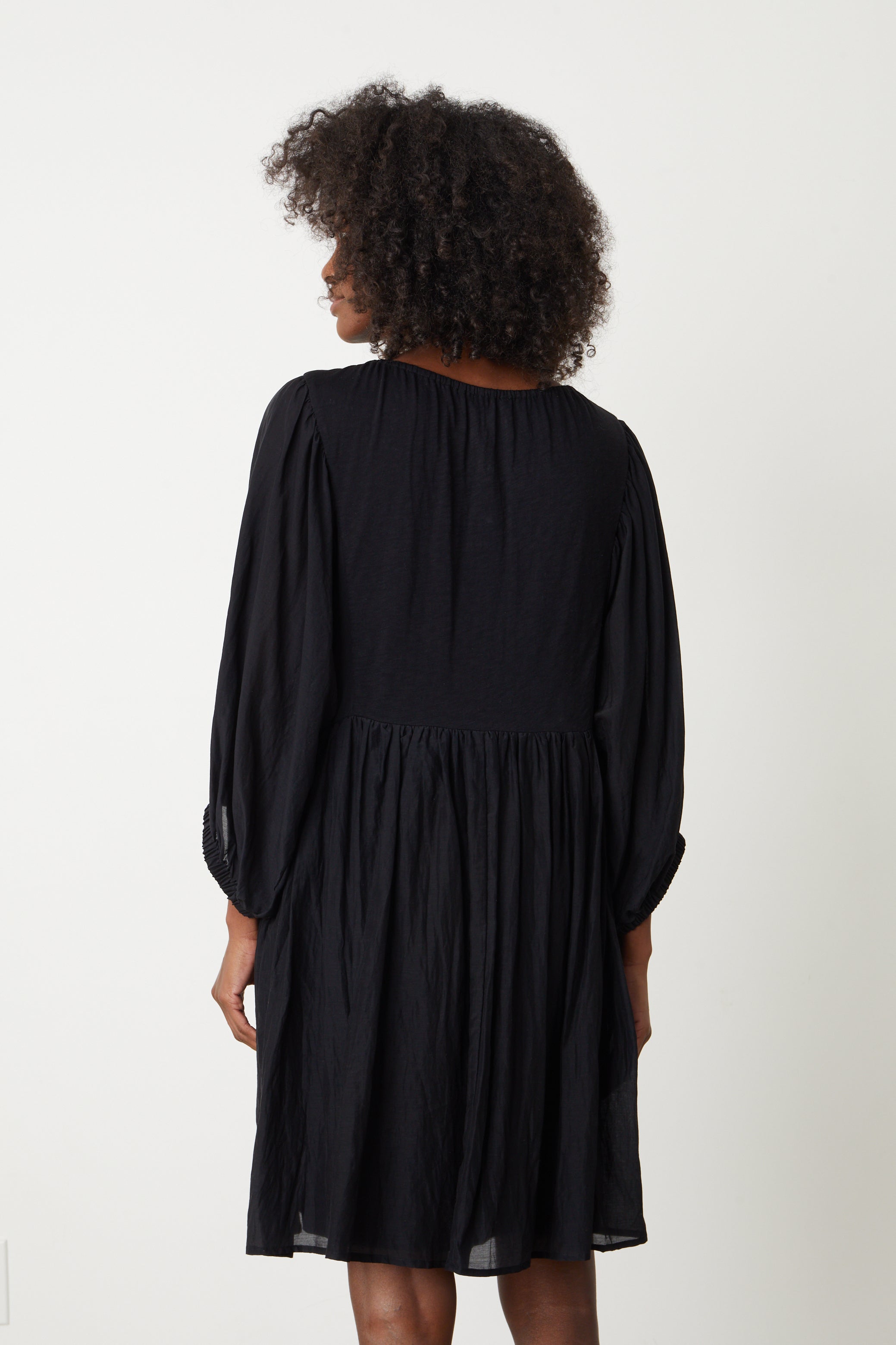   The back view of a woman wearing the ERIN SHIRRED WAIST DRESS by Velvet by Graham & Spencer. 