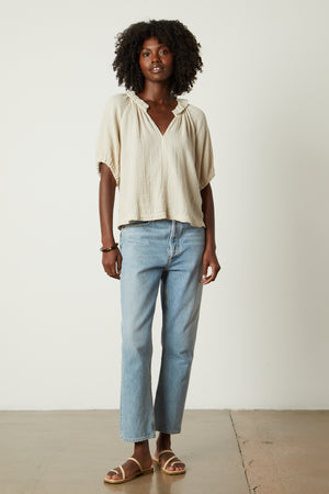The model is wearing a Velvet by Graham & Spencer Ilene Puff Sleeve Top and jeans with a relaxed fit.