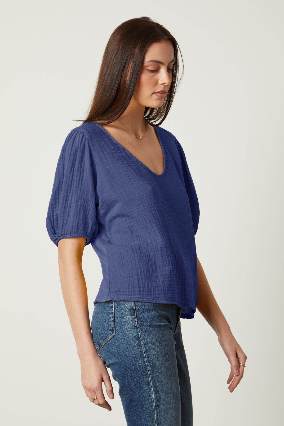  a woman wearing jeans and a blue Velvet by Graham & Spencer Louisa puff sleeve top. 
