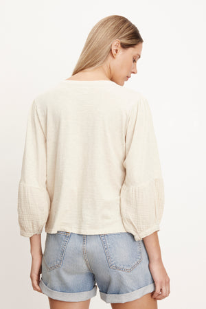 the back view of a woman wearing denim shorts and a Velvet by Graham & Spencer MARIEL PUFF SLEEVE TEE.