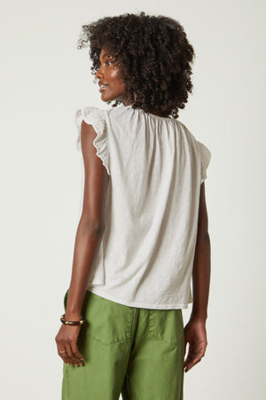 the back view of a woman wearing green pants and a Velvet by Graham & Spencer REMI RUFFLE SLEEVE TOP.