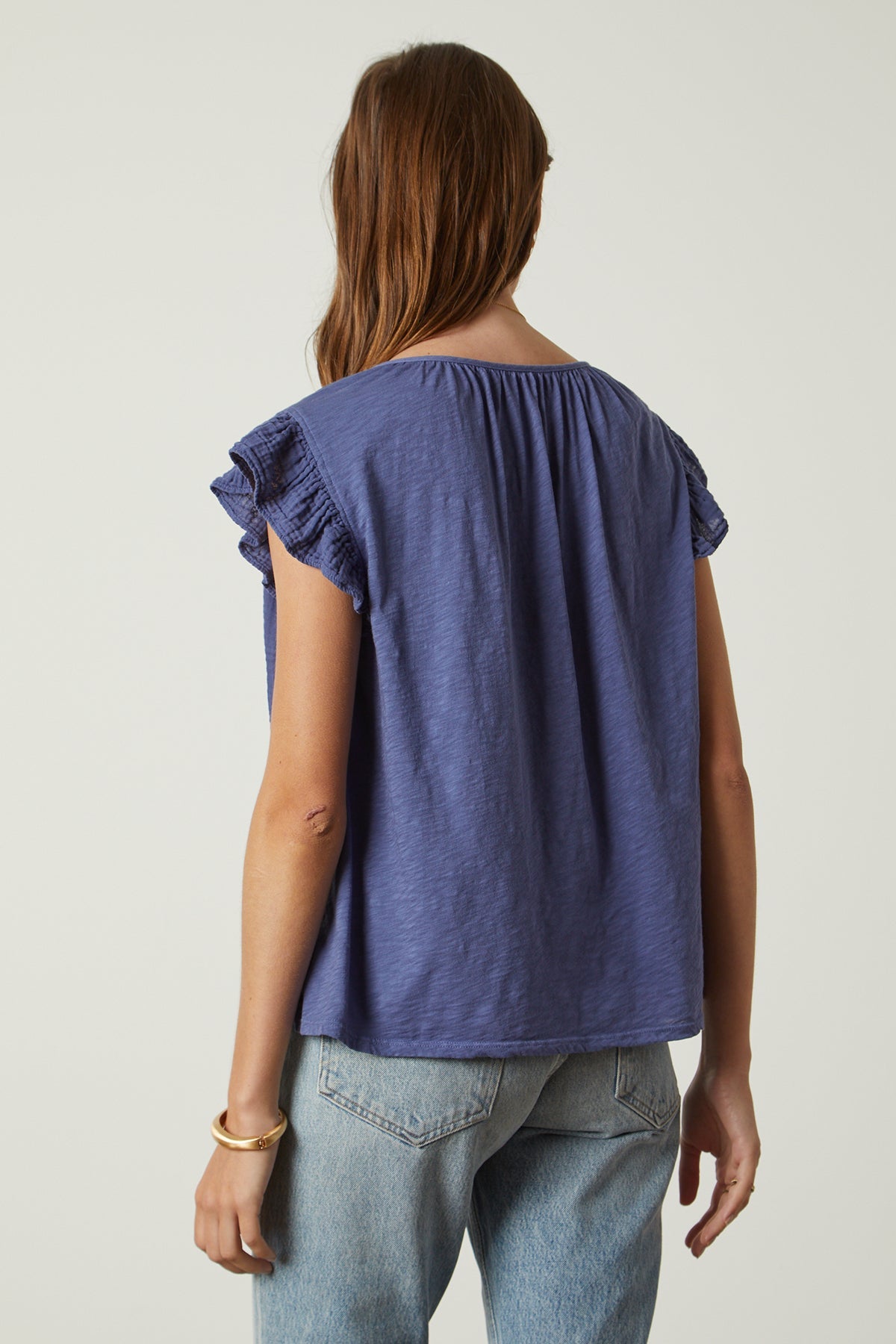 the back view of a woman wearing Velvet by Graham & Spencer's REMI RUFFLE SLEEVE TOP with blue ruffled sleeves.-26631974092993