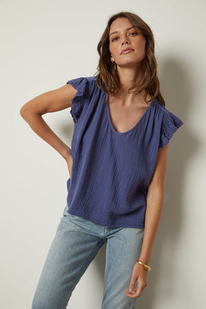 the model is wearing REMI RUFFLE SLEEVE TOP jeans and a blue top by Velvet by Graham & Spencer.
