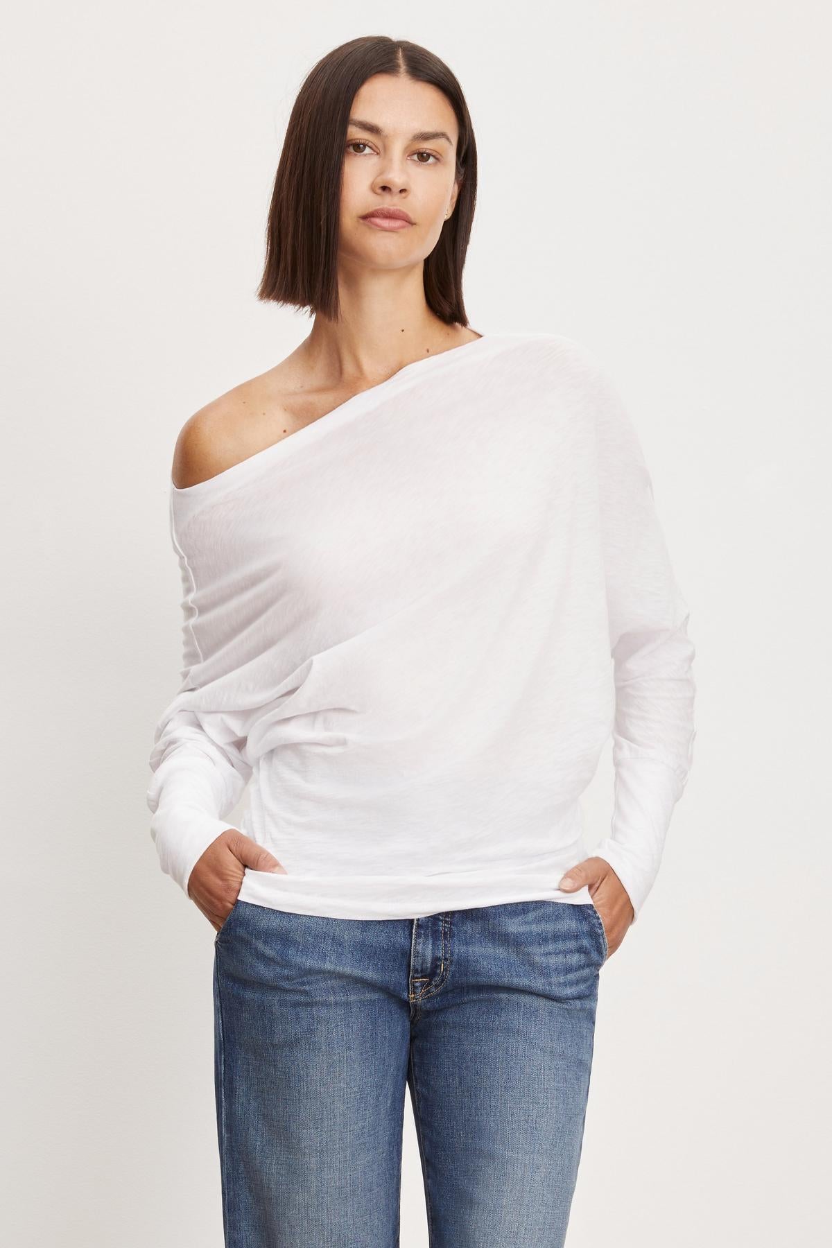 The model is wearing a white off-shoulder Velvet by Graham & Spencer NOVALEE DOLMAN TEE.-35701726609601