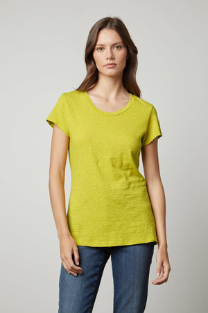 A woman wearing a yellow Velvet by Graham & Spencer ODELIA COTTON SLUB CREW NECK TEE and jeans.
