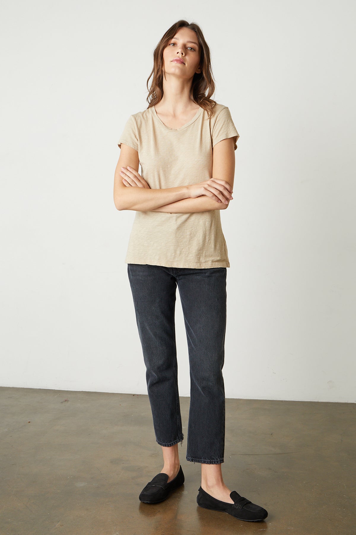   Model standing with arms folded wearing Odelia Crew Neck Tee in sesame with black denim and black flats full length front 