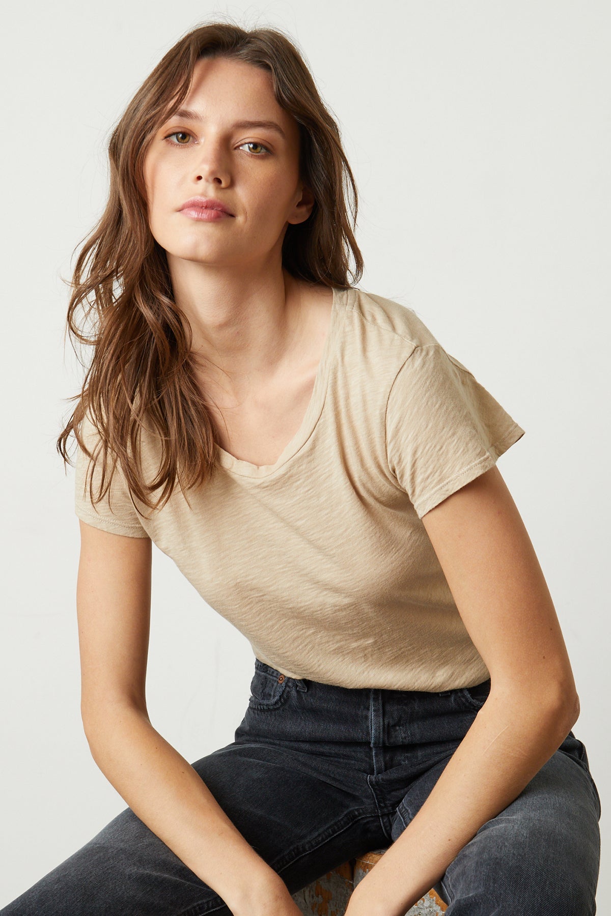 Model sitting wearing Odelia Crew Neck Tee in sesame with black denim -26631432274113