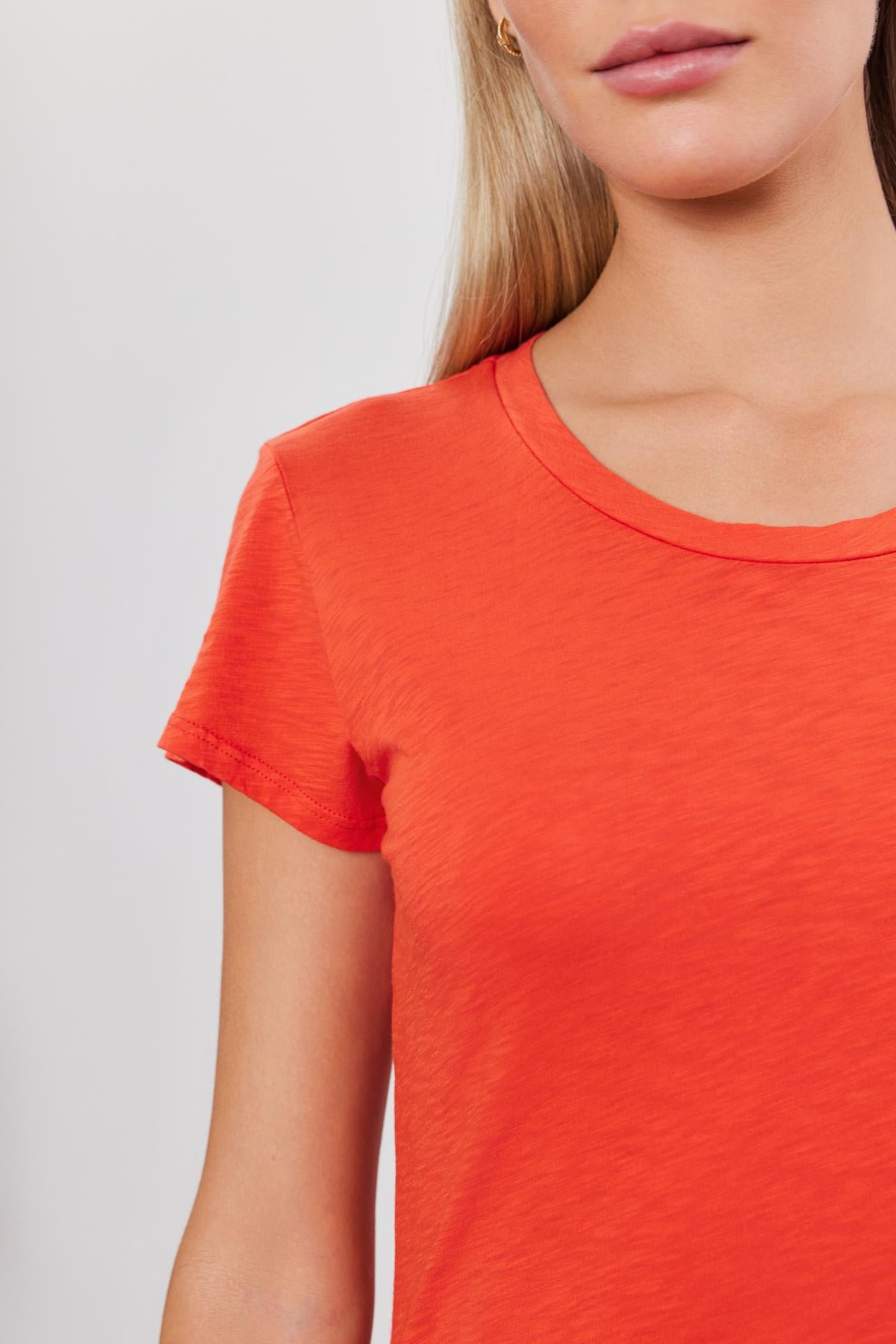 Close-up of a woman wearing a bright red ODELIA COTTON SLUB CREW NECK TEE by Velvet by Graham & Spencer, focusing on the shoulder and neckline details.-36910072529089
