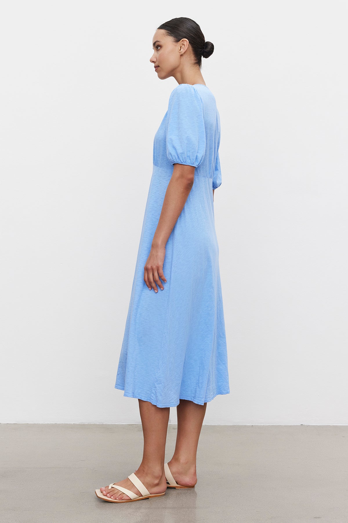 Woman in a blue Velvet by Graham & Spencer PARKER COTTON SLUB MIDI DRESS and beige sandals standing in profile against a white background.-36691474776257