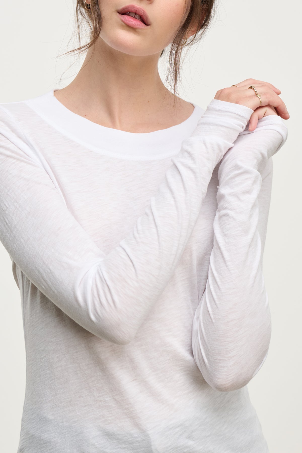 A woman models the PRIYA TEE by Velvet by Graham & Spencer—a sheer white, relaxed-fit long-sleeve shirt—arms slightly crossed, minimal jewelry, against a neutral background; an effortlessly versatile wardrobe staple.-39814912639169