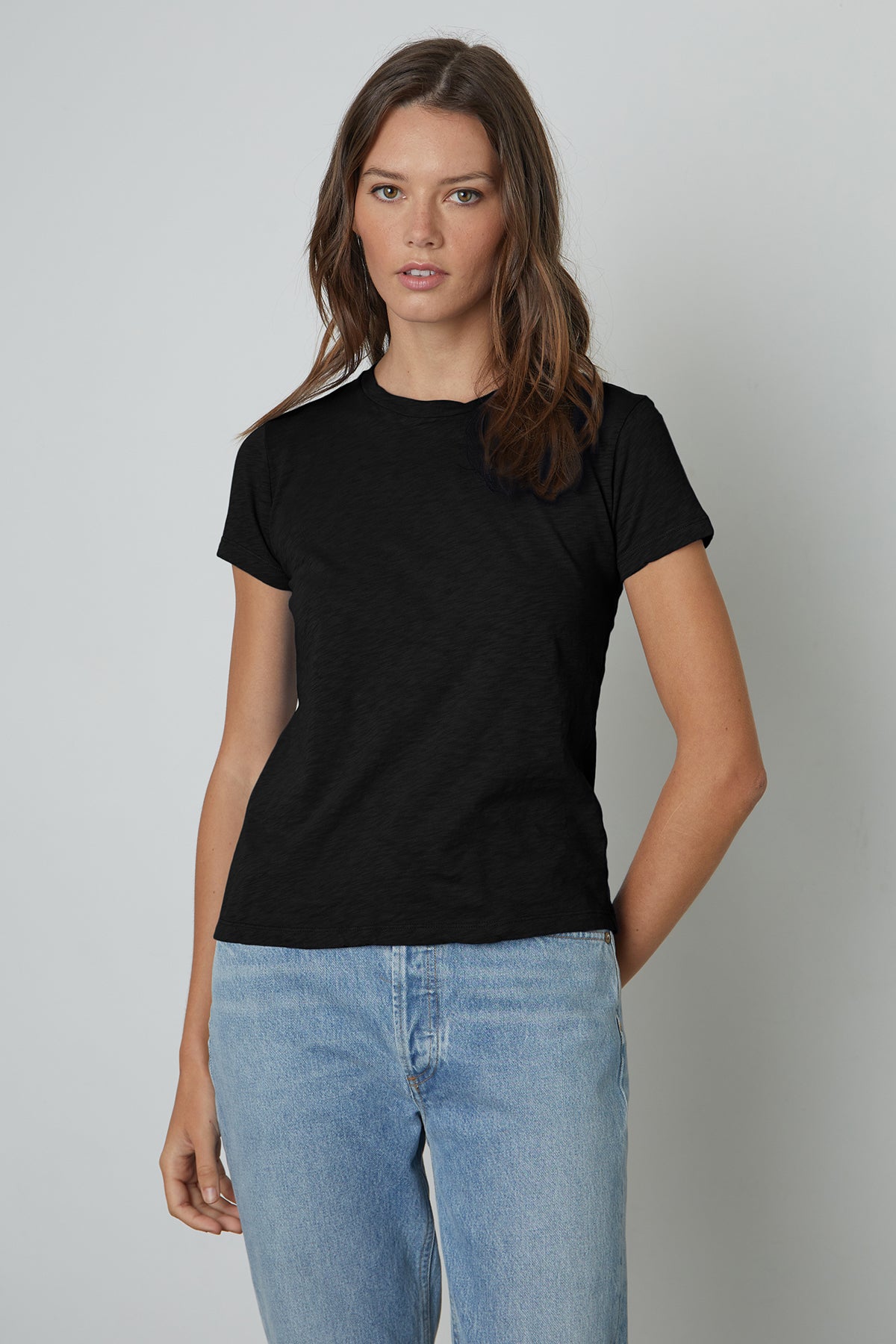  A woman wearing a black Velvet by Graham & Spencer SIERRA CREW NECK TEE and jeans. 