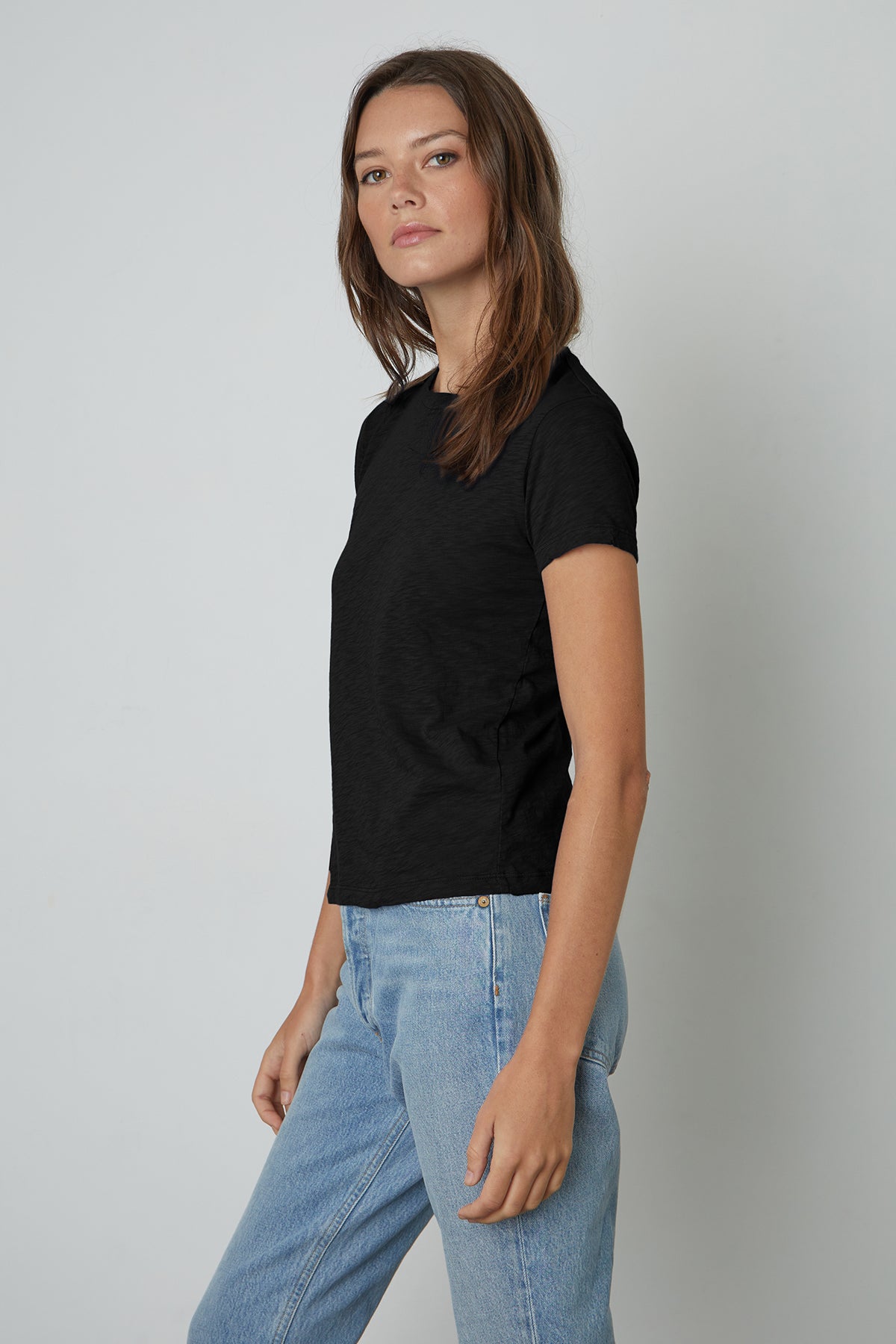   A woman wearing a black SIERRA CREW NECK TEE by Velvet by Graham & Spencer and jeans. 