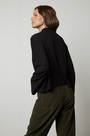 The back view of a person wearing Velvet by Graham & Spencer olive pants and a STACEY MOCK NECK TEE.