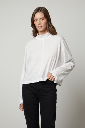 The model is wearing a white STACEY MOCK NECK TEE by Velvet by Graham & Spencer and black jeans.