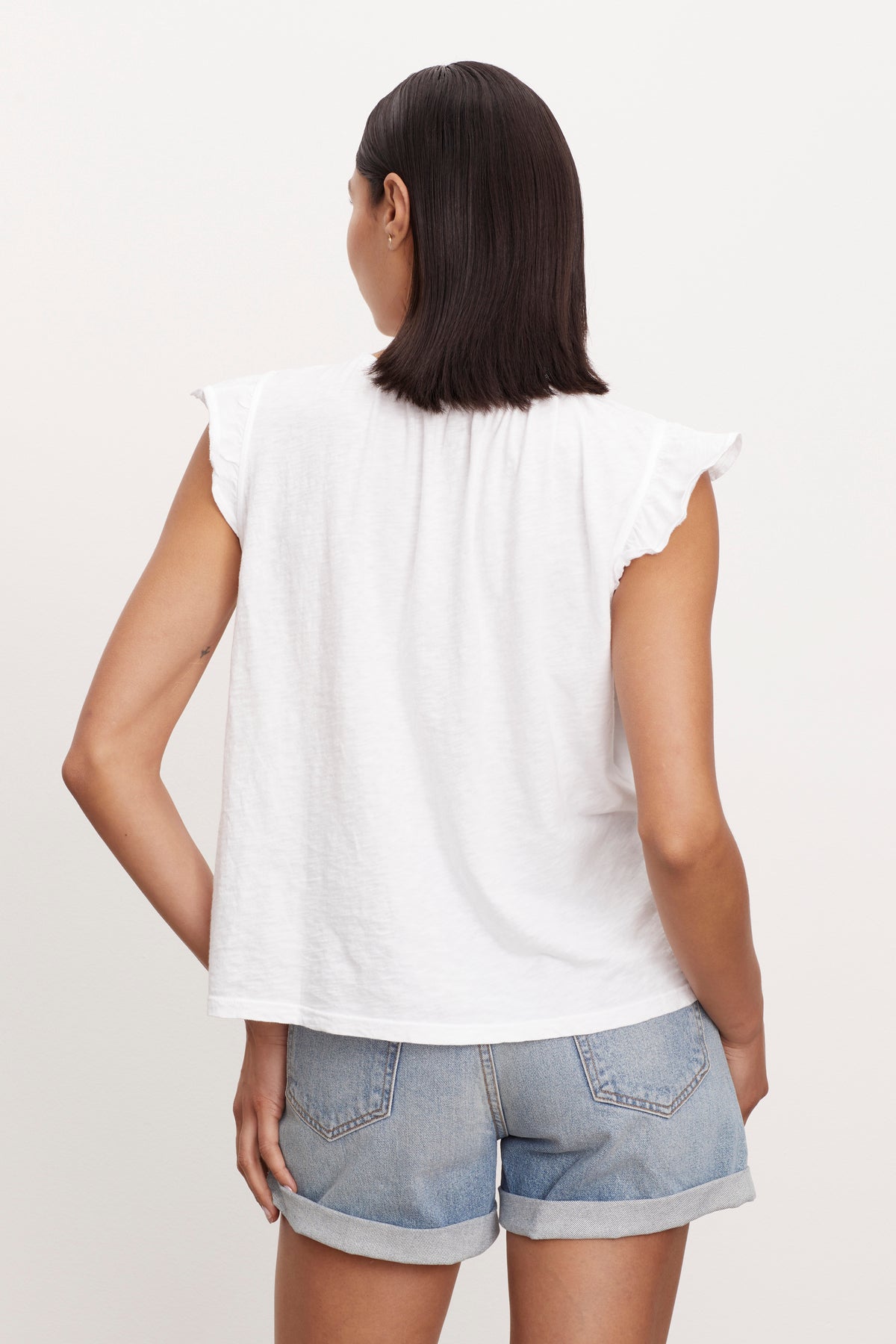   the back view of a woman wearing denim shorts and a Velvet by Graham & Spencer STACY RUFFLE SLEEVE TANK. 