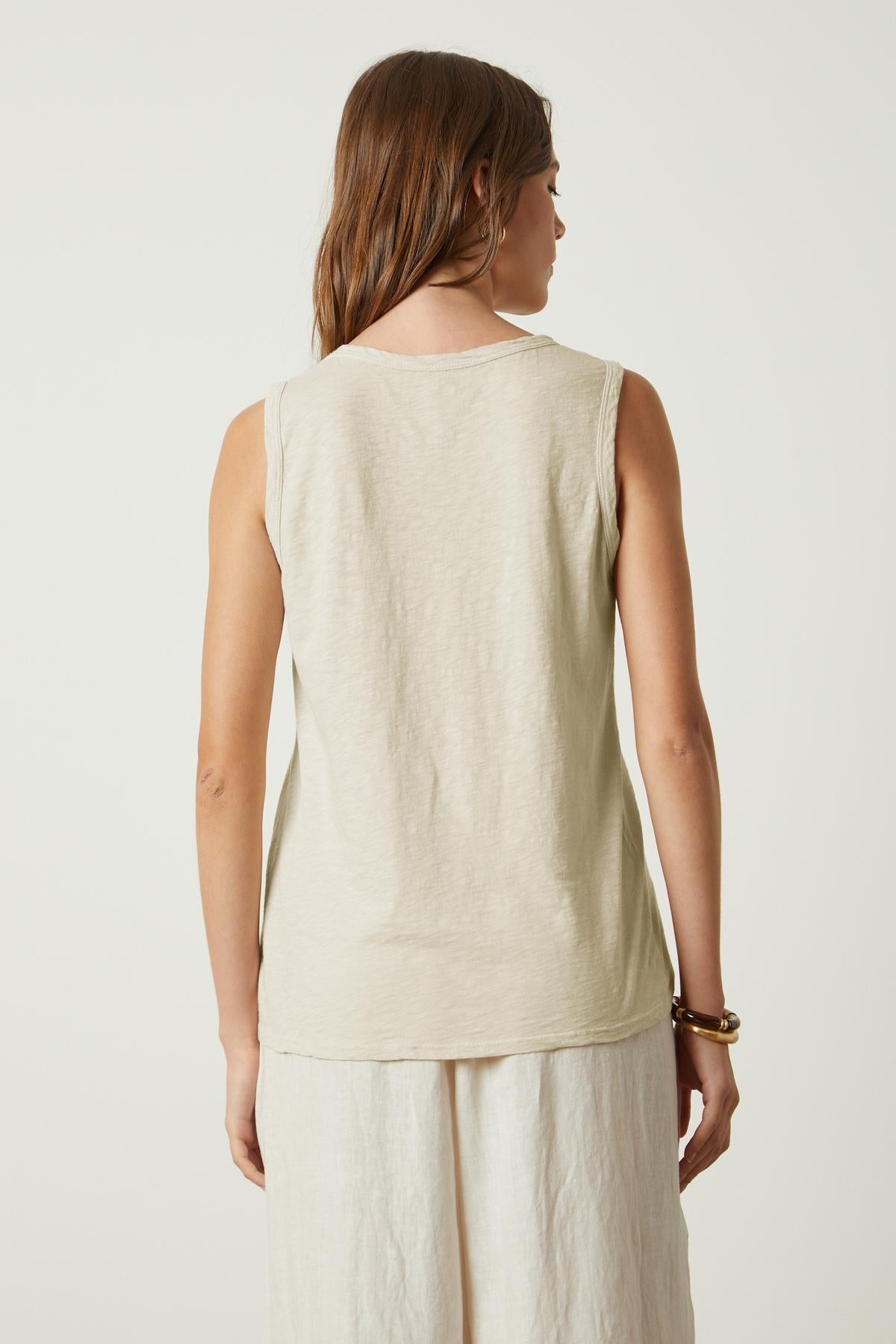 The back view of a woman wearing a Velvet by Graham & Spencer TAURUS COTTON SLUB TANK in beige.-35567717777601