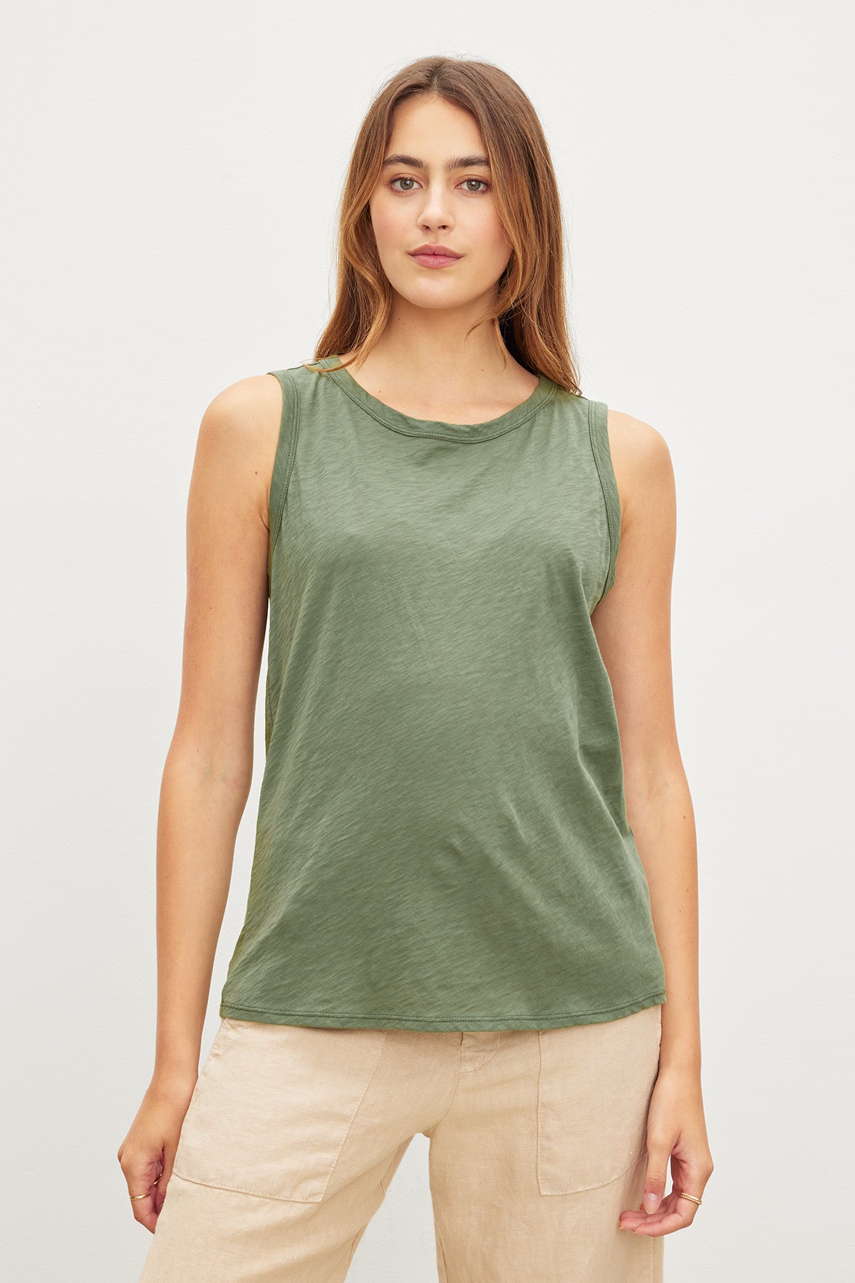   A woman in a Velvet by Graham & Spencer TAURUS COTTON SLUB TANK tank top and beige pants standing against a plain background. 