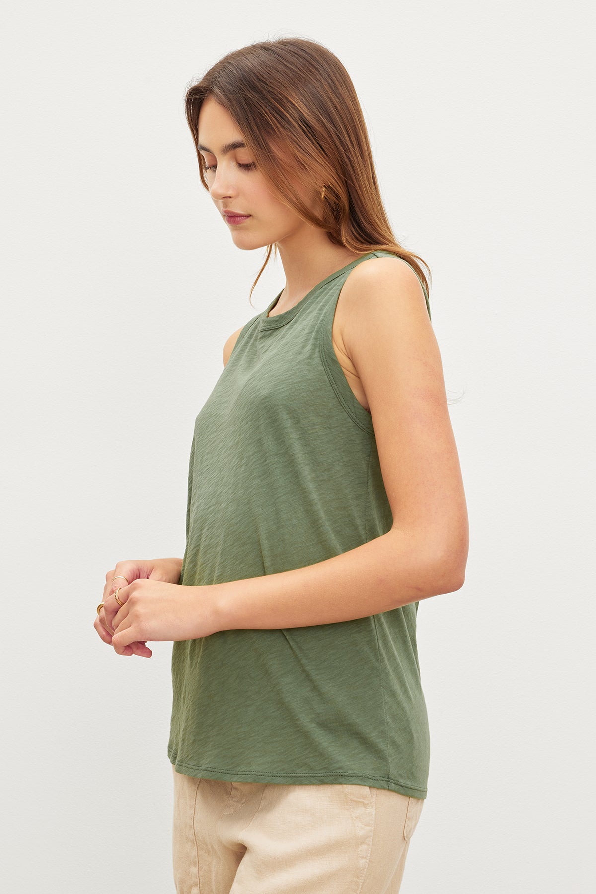   A woman in a Velvet by Graham & Spencer TAURUS COTTON SLUB TANK and beige pants, standing with her eyes closed and hands gently clasped together. 