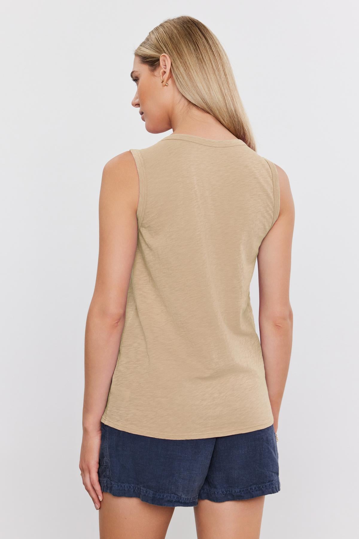   Woman wearing a beige TAURUS COTTON SLUB TANK and denim shorts, seen from the back, standing against a white background. (Brand Name: Velvet by Graham & Spencer) 