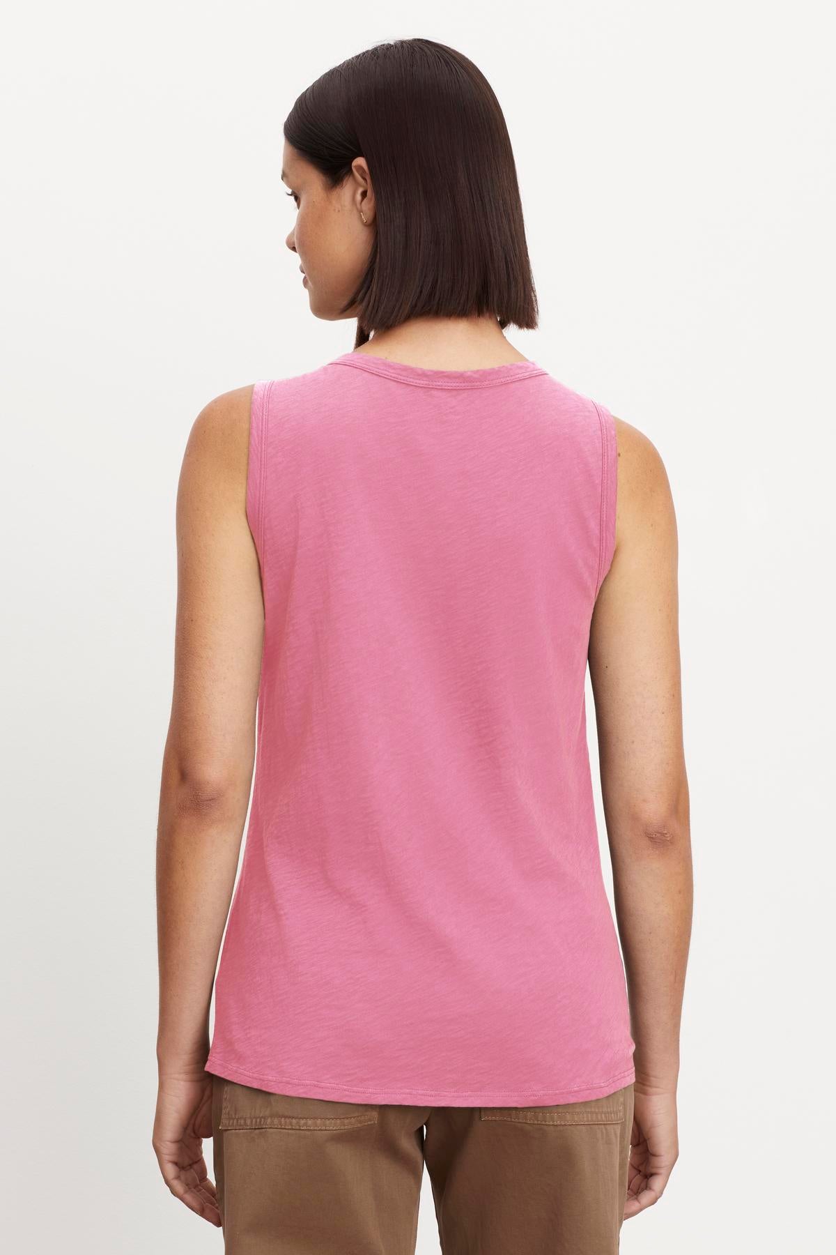   A person with short dark hair is seen from behind, wearing a sleeveless TAURUS TANK TOP made of textured cotton slub by Velvet by Graham & Spencer and brown pants. 