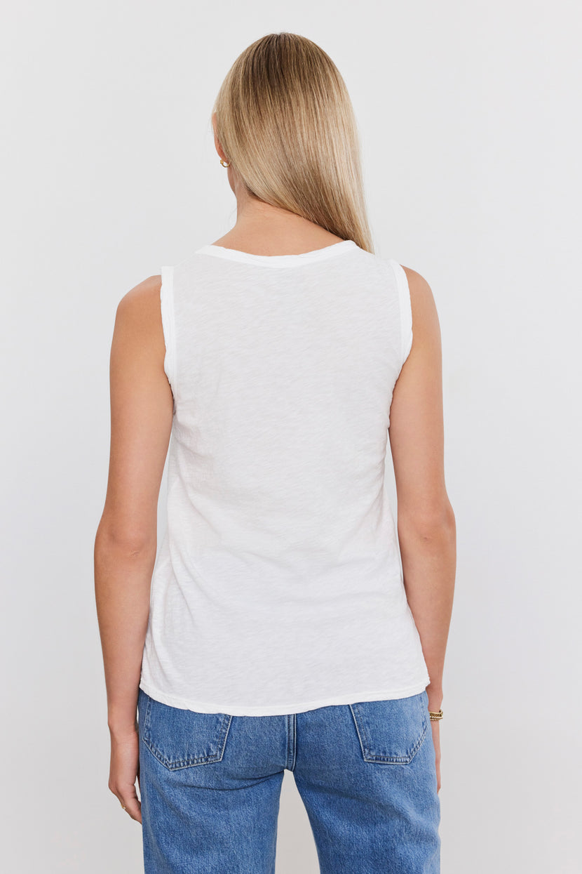 A person with long blond hair is shown from behind wearing a white, sleeveless textured cotton slub Velvet by Graham & Spencer TAURUS TANK TOP and blue jeans.