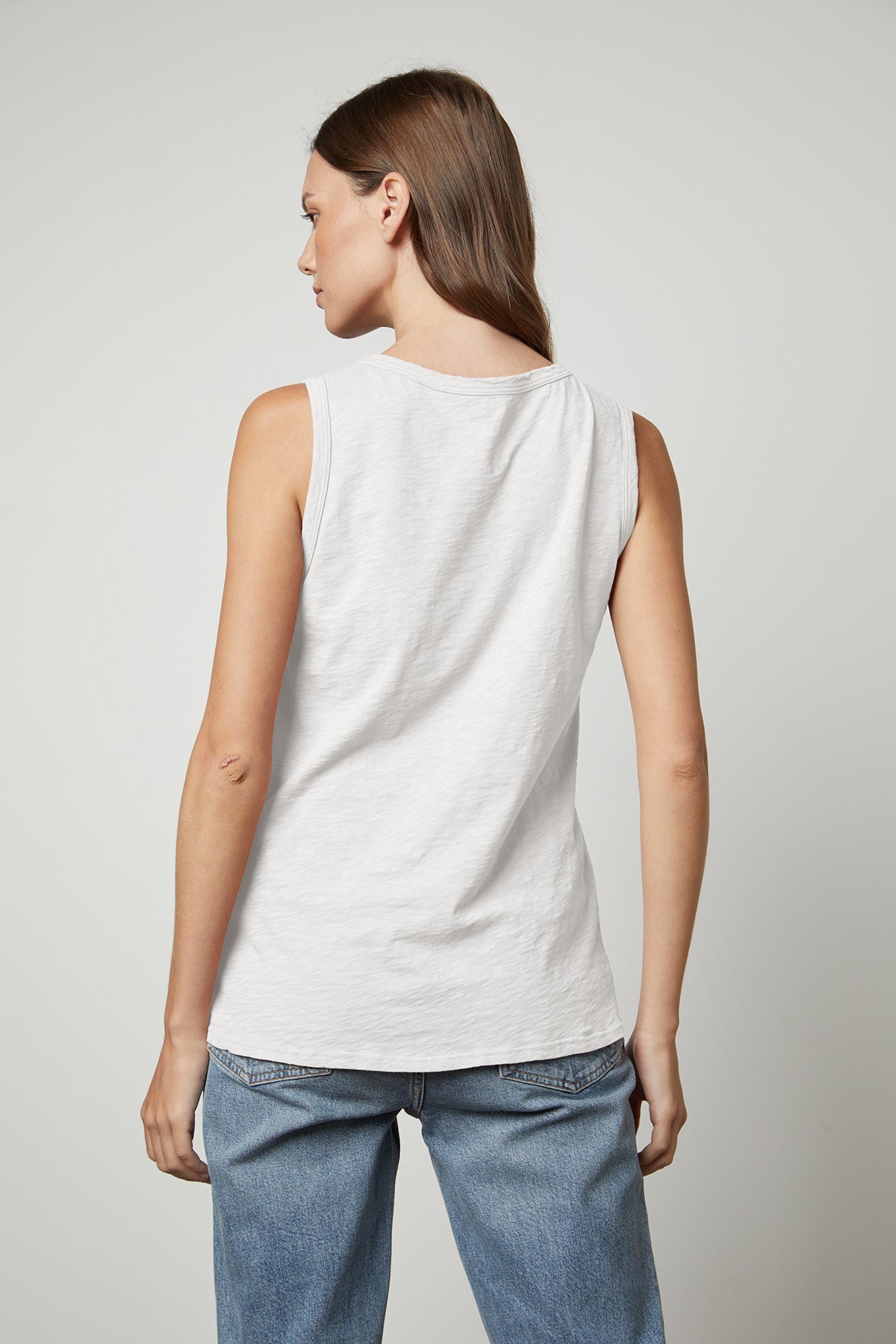 The back view of a woman wearing a Velvet by Graham & Spencer TAURUS COTTON SLUB TANK and jeans.-26632370651329