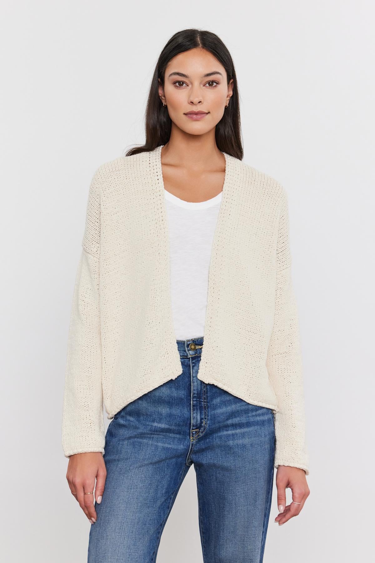 Woman in a Velvet by Graham & Spencer HOLLIE CARDIGAN, white t-shirt, and blue jeans standing against a plain background.-36752930406593