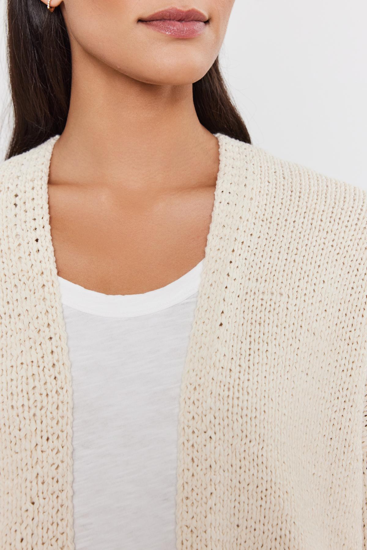   Close-up of a woman wearing a Velvet by Graham & Spencer HOLLIE CARDIGAN over a white top, focusing on the neckline area. 