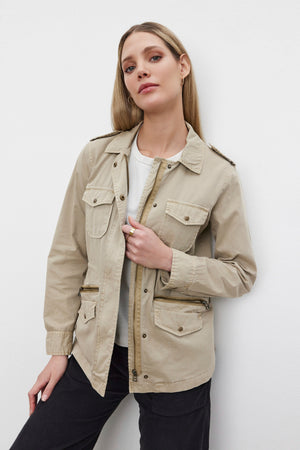 A person is standing against a white background wearing the RUBY LIGHT-WEIGHT ARMY JACKET by Velvet by Graham & Spencer, crafted from beige cotton twill and featuring practical pockets, over a white shirt.