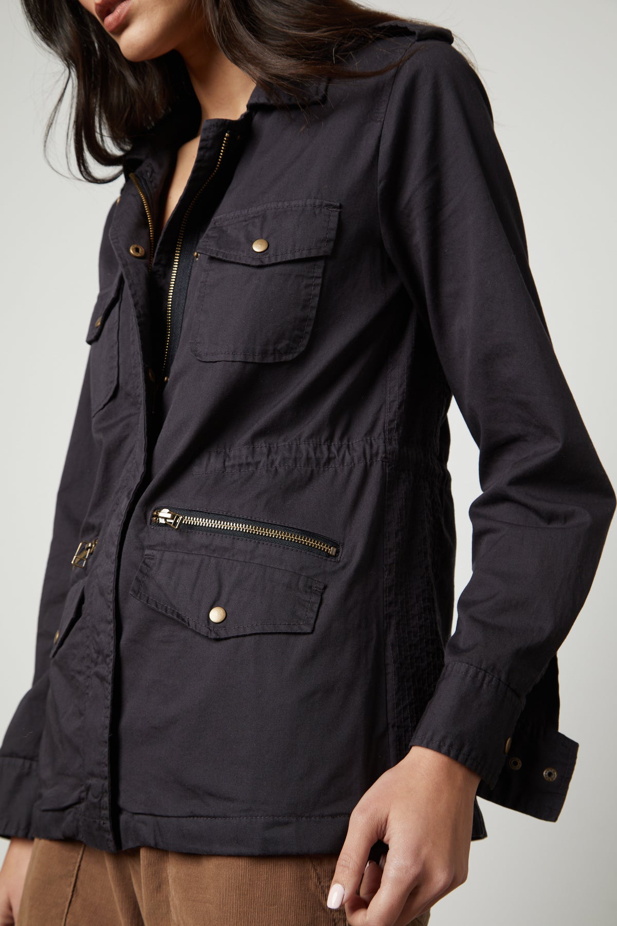 A woman wearing a RUBY LIGHT-WEIGHT ARMY JACKET by Velvet by Graham & Spencer with zippers and pockets adds versatility to her closet.-35783096598721