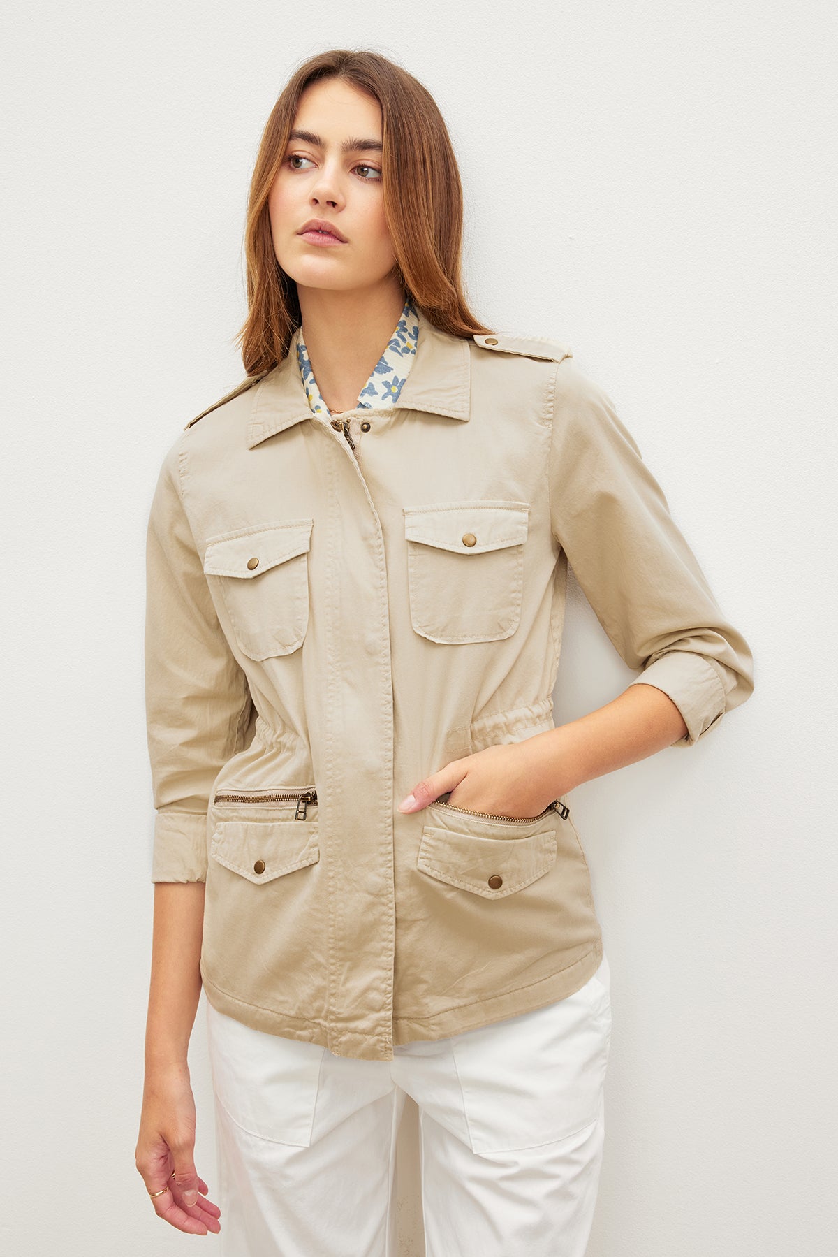   A versatile woman wearing a Velvet by Graham & Spencer RUBY LIGHT-WEIGHT ARMY JACKET with white pants. 