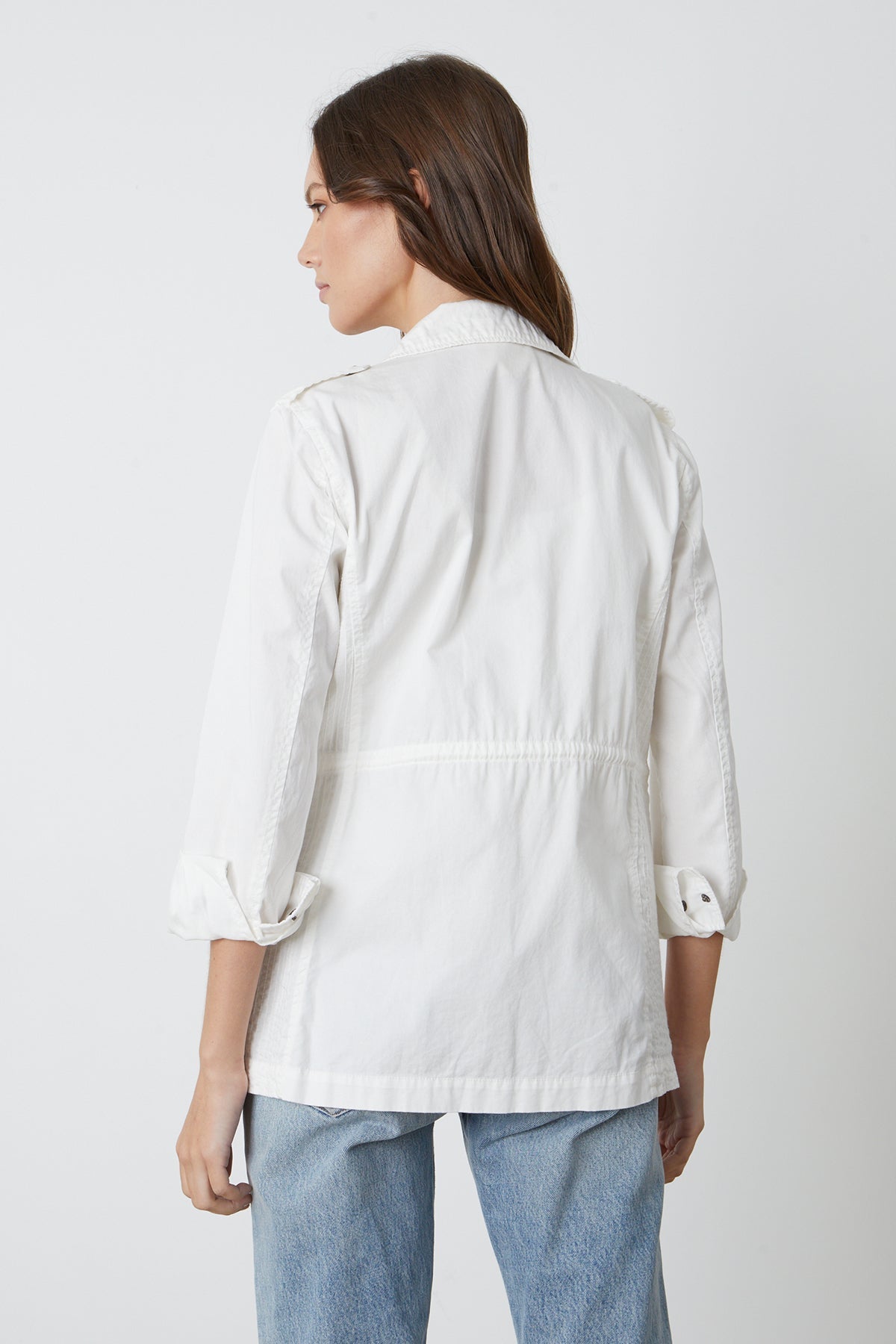   The back view of a woman wearing a Velvet by Graham & Spencer RUBY LIGHT-WEIGHT ARMY JACKET and jeans. 