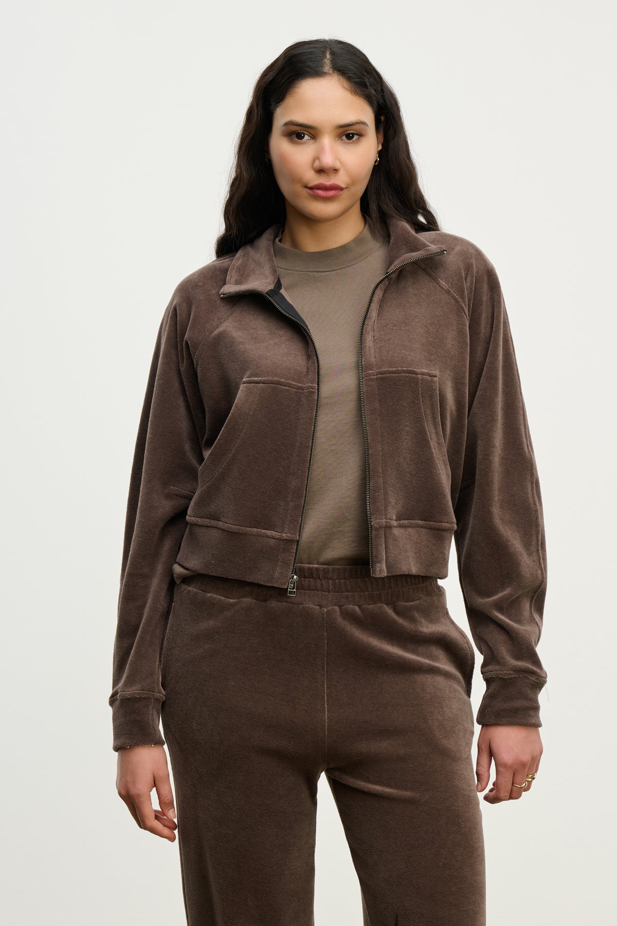   A woman faces forward against a light background, wearing the CLAIRE JACKET by Velvet by Graham & Spencer—a brown cotton velour hoodie—paired with matching pants over a taupe shirt. 