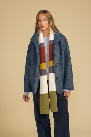 A person wearing a blue jacket, a light blue top, and the Velvet by Graham & Spencer JADE SCARF stands against a beige background.