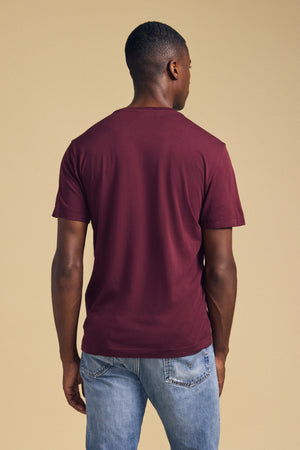Back view of a person wearing a maroon short-sleeved HOWARD TEE by Velvet by Graham & Spencer and blue jeans for a perfect fit.