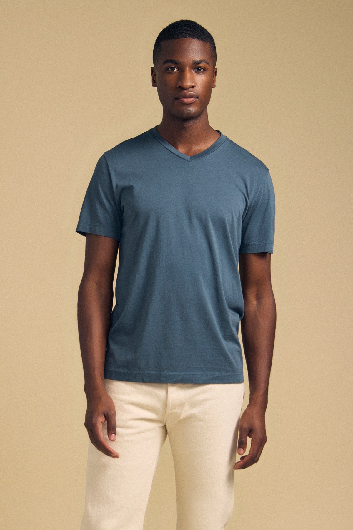 A man wearing a slate blue SAMSEN TEE Pima jersey V-neck T-shirt and cream-colored pants.