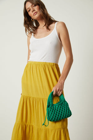 The model is wearing a Velvet by Graham & Spencer Danielle Cotton Gauze Tiered Skirt and green bag.