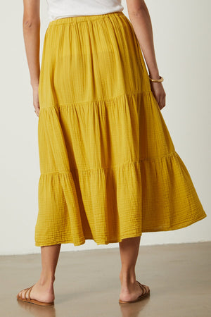 The back view of a woman wearing a yellow Danielle Cotton Gauze Tiered Skirt by Velvet by Graham & Spencer.